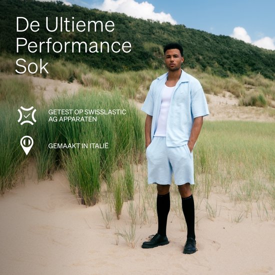Man op het strand draagt zwarte STOX Energy Socks en een lichtblauwe outfit.