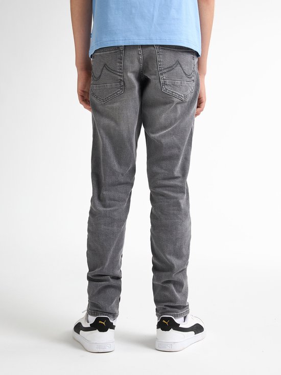 Jongen in lichtblauwe T-shirt en grijze jeans, achterkant zichtbaar.