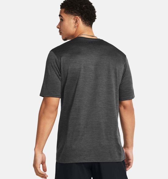 Man, achterkant van grijs sportshirt met fijne zwarte horizontale strepen en zwart Under Armour logo op de nek.