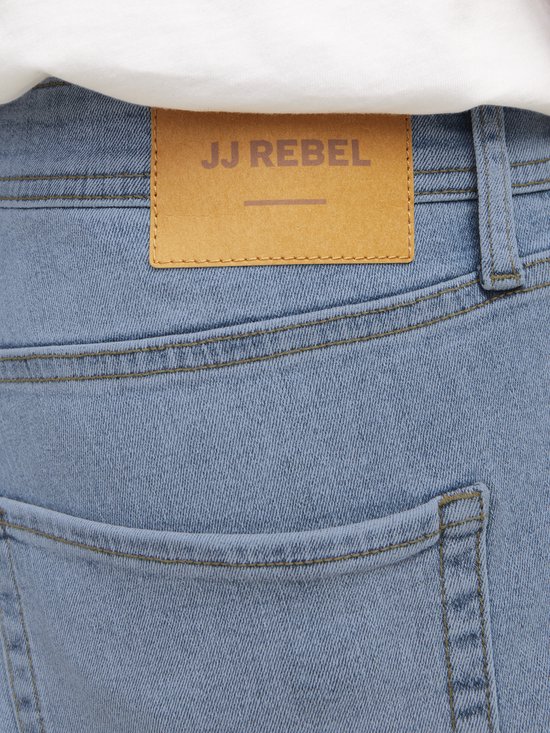 Lichtblauwe jeans met een bruin leren merklabel 'JJ Rebel' op de achterkant.