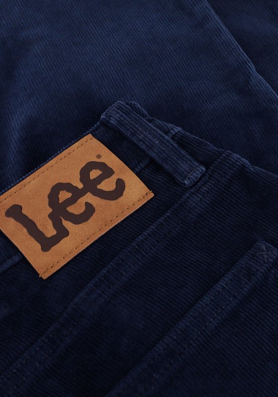 Detail van het bruine Lee logo op een donkerblauwe corduroy broek.