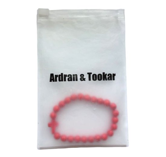 Een rode kralenarmband met kruis in een Ardran & Tookar verpakking.