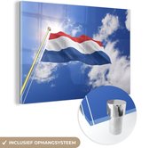 MuchoWow® Glasschilderij 180x120 cm - Schilderij acrylglas - De vlag van Nederland wappert in de lucht - Foto op glas - Schilderijen