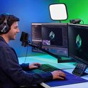 Man met koptelefoon gebruikt Stream Deck+ bij een bureau met twee computerschermen.