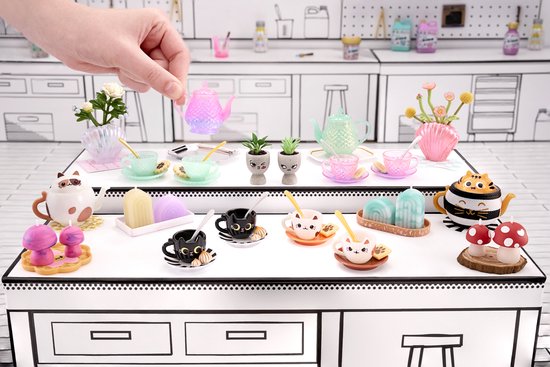 Een display met miniatuur kopjes, schoteltjes en theepotten, met katten- en paddenstoelthema.