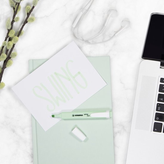 Een STABILO swing cool lichtgroene markeerstift op een notitieboek met de tekst 'SWING' erop.