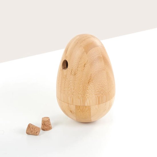 Eivormige bamboe voerpuzzel met een gat en twee kurken dopjes ernaast.