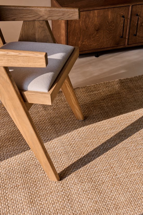 Chaise en bois avec assise beige sur un tapis beige tissé plat.