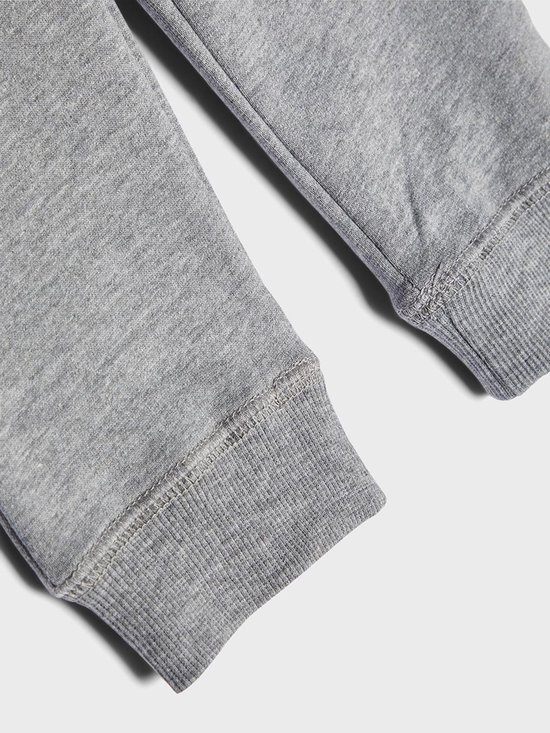 Detail van de geribbelde boorden van een grijze joggingbroek.