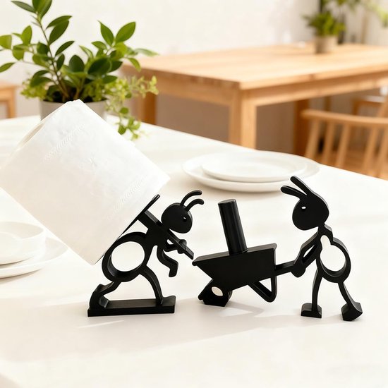 Zwarte ant toiletrolhouders op een tafel. Eén rol toiletpapier wordt gedragen op de rug van een mier, de ander wordt geduwd in een kruiwagen.