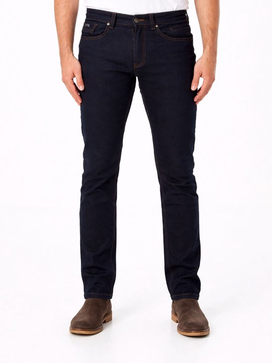Man met donkerblauwe slim fit jeans, met bruine stiksels en bruine schoenen.