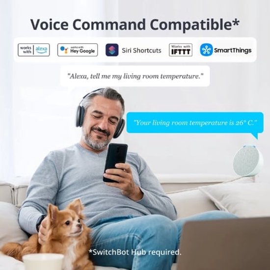 Man zit op bank met telefoon, draadloze koptelefoon op en hondje op schoot. Tekst: 'Voice Command Compatible'.