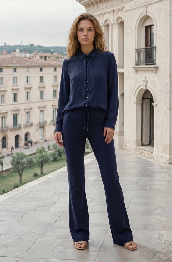 Model met donkerblauwe, wijde broek en bijpassend gestrikt overhemd.