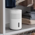 Witte Pro Breeze luchtontvochtiger op een plank in een kast, tussen kleding.