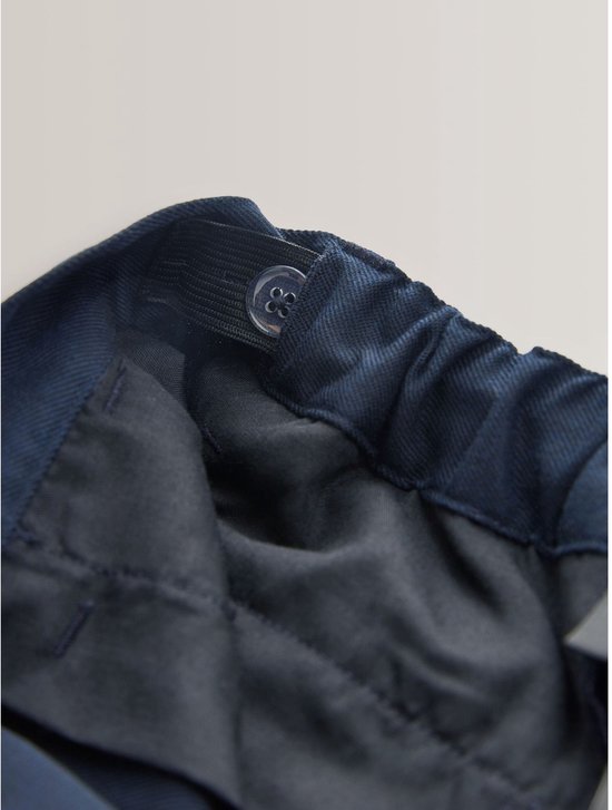 Binnenzijde van een donkerblauwe broek met elastische tailleband en verstelbare knopen.