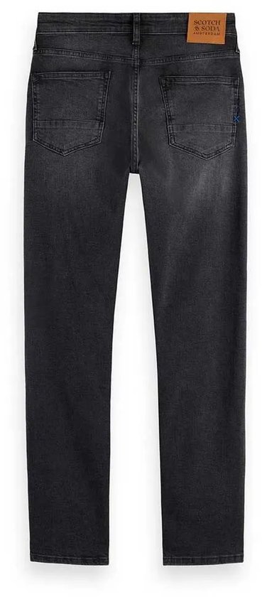 Achterkant van een donkergrijze jeans met leren merklabel.