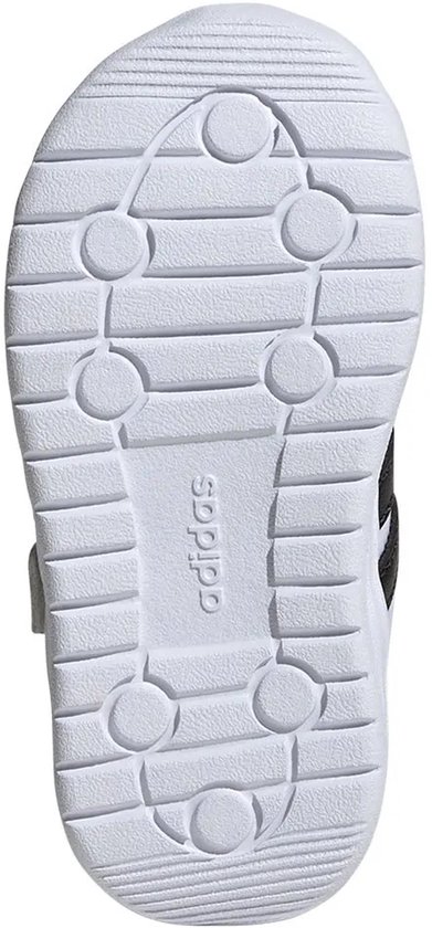 Onderkant van witte kindersneaker met Adidas-logo en groeven.