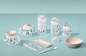 Babyproducten met pastelkleurige regenboog- en ballonmotieven, waaronder drinkbekers, stapelbare bewaarbakjes en een kom.