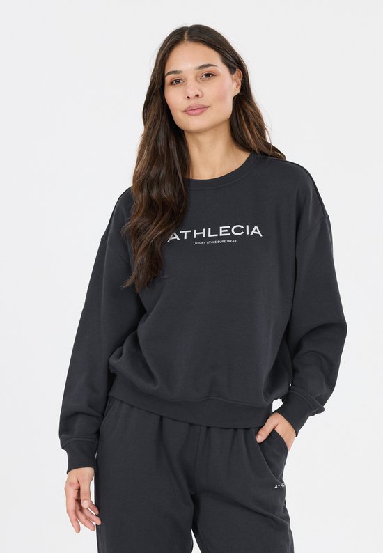 Model draagt een zwarte sweater met ronde hals en witte 'ATHLECIA LUXURY ATHLEISURE WEAR' tekst.