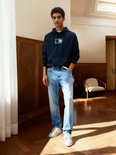 Man in donkerblauwe hoodie en jeans met lichte wassing.