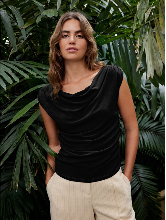 Model in zwarte top met gedrapeerde halslijn en gerimpelde zijkanten.