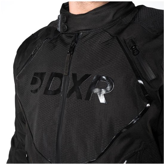 Close-up van zwarte motorjas met DXR-logo, hexagon-textuur en glanzende accenten.