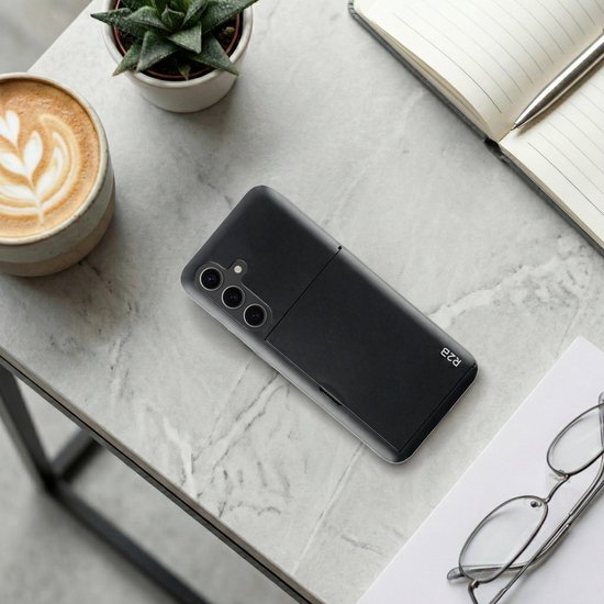 Zwart R2B telefoonhoesje met pasjeshouder op een marmeren tafel, naast een kop koffie, plantje en bril.