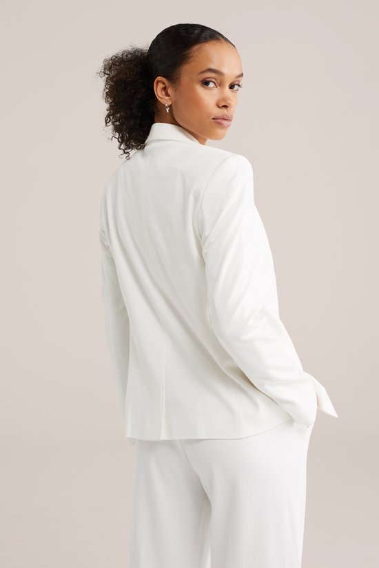 Model draagt een witte getailleerde blazer van achteren gezien. De blazer heeft een enkele knoopsluiting.