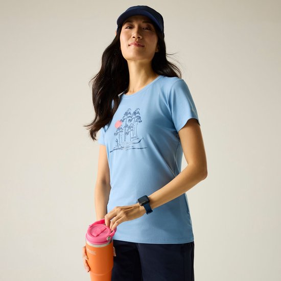 Vrouw met donker haar en pet op, draagt lichtblauwe T-shirt met opdruk en donkerblauwe short.