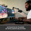 Homme avec un casque jouant à des jeux vidéo derrière deux écrans d'ordinateur, avec une webcam et un microphone.