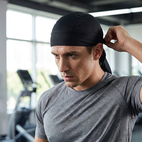 Man met baard past een zwarte mesh bandana aan in een fitnessruimte.