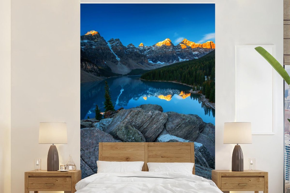 Behang - Fotobehang Zonsopgang met een weerspiegeling van de bergen bij het Moraine Lake in Canada - Breedte 170 cm x hoogte 260 cm