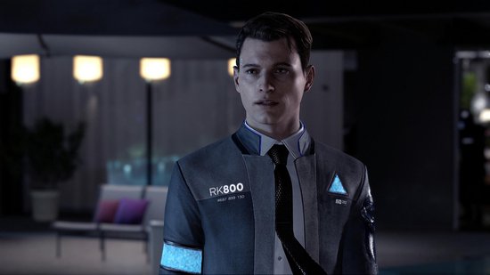 Jonge man met kort bruin haar, draagt een grijs pak met RK800 opdruk en blauwe banden.
