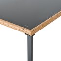 Detail van de hoek van een tafel met een bruine rotan rand en een zwart glazen tafelblad.