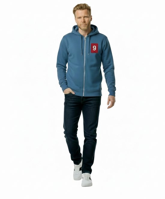 Man in blauw vest met rits, spijkerbroek en witte sneakers. Op de borst een rood vak met cijfer 9.