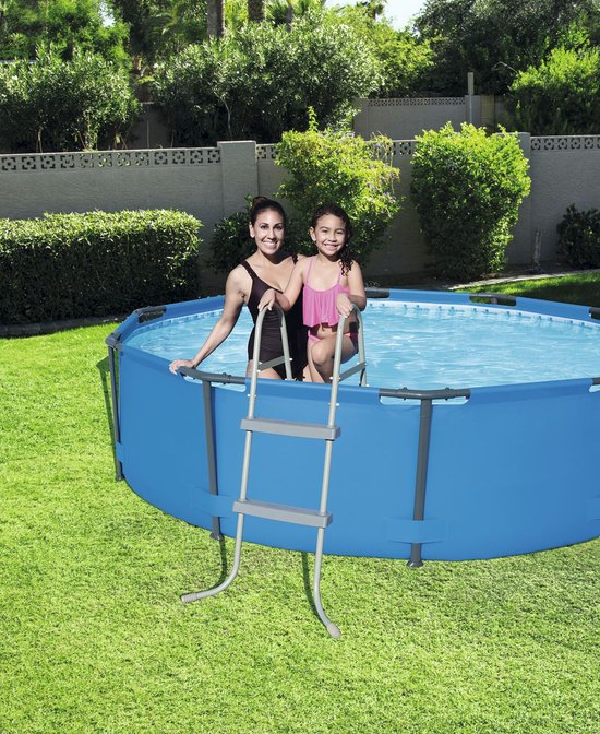 Vrouw en meisje in badkleding bij een ronde blauwe zwembad met een grijze ladder.