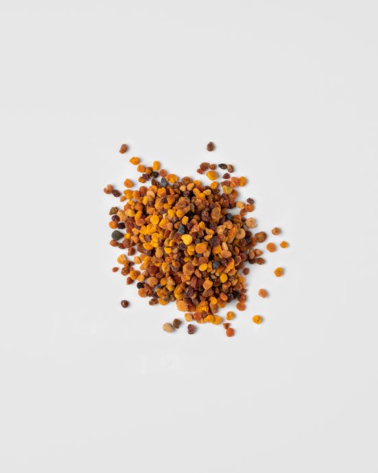 Een hoopje biologische bijenpollen stuifmeelkorrels op een witte achtergrond.
