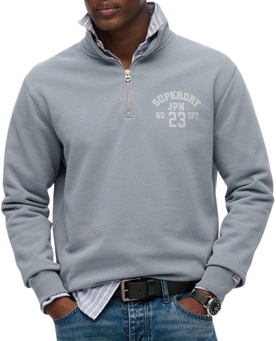 Sweatshirt gris avec fermeture éclair, inscription Superdry JPN NO. 23 DPT, porté par un homme.
