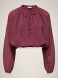 Bordeauxrode blouse met ruches, strikdetail en gouden knoopjes aan de zoom.