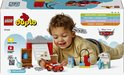 Een jongetje speelt met LEGO Duplo Cars. Hij heeft de rode Lightning McQueen auto, Doktersgarage en andere accessoires.