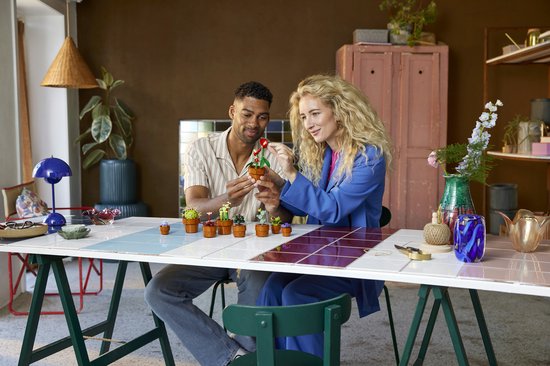 Man en vrouw bouwen aan LEGO planten, met een tafel vol gebouwde plantjes.