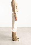 Model draagt beige suède laarzen met drie lagen franjes.