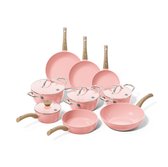 Een complete set roze pannen met houten handvatten op een zwarte achtergrond.