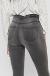 Achterkant van een grijze skinny jeans met merklogo op de tailleband.