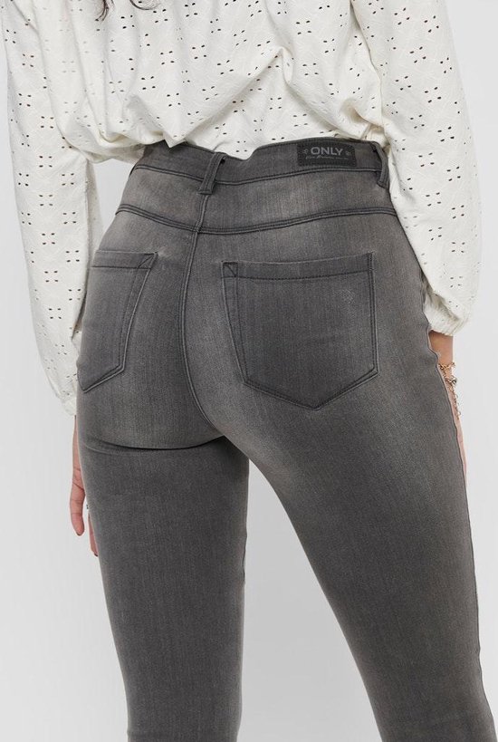 Achterkant van een grijze skinny jeans met merklogo op de tailleband.