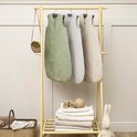 Drie baby slaapzakken hangen aan een rek: groen, grijs en zandkleurig. De zandkleurige slaapzak is gevoerd.