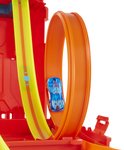 Une voiture Hot Wheels bleue fait un looping sur une piste orange, partie du set Hot Wheels Track Builder rouge.