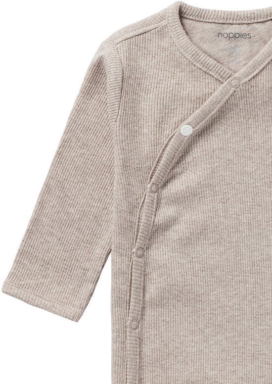 Detail van een beige longsleeve boxpakje met overslagsluiting en drukknoopjes.