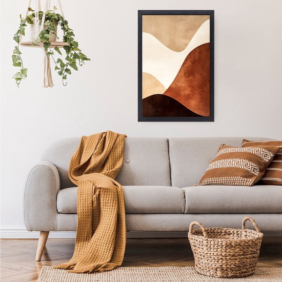 Abstract schilderij met golvende vormen in bruin- en beige tinten hangend boven een grijze bank met een gele plaid.