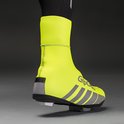 Neongele fietsoverschoen op een fietsschoen met zwarte fietsbroek en reflecterende strepen.
